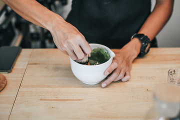 A brush made of bamboo and a teacup with green tea called matcha on wooden tray made by professional barista in Asian cafe.Green tea powder being stir in a white ceramic bowl.Tea ceremony in oriental 