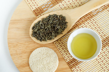 Olive oil, dry green tea leaves and loofah sponge. Ingredients for preparing homemade mask. Natural beauty treatment recipe and zero waste concept. Top view, copy space.