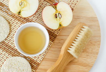 Apple juice (vinegar) and wooden massage body brush. Ingredients for preparing homemade hair mask or face toner. Natural beauty treatment recipe and zero waste concept. Top view, copy space.