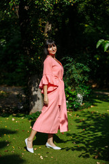 young woman in pink dress spinning in the garden