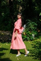 young woman in pink dress spinning in the garden