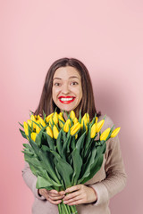Young woman with  bouquet of tulips on color background