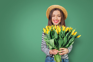 Young woman with  bouquet of tulips on color background