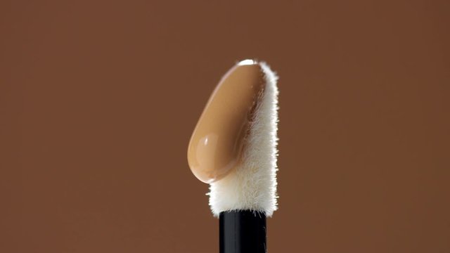 white concealer stick and a drop of concealer pouring on it. Macro of concealer stick with product drop