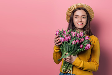 Young woman with  bouquet of tulips on color background