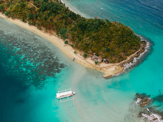 a boat anchored between two small tropical islands in palawan, philippines