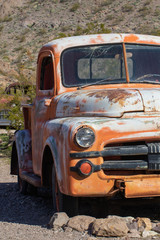 Vintage orange pickup truck rusting in the desert