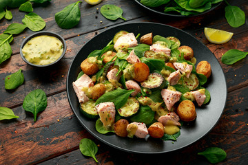 Salmon, new potato, courgette and spinach salad on wooden table