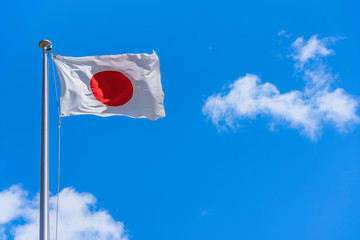 Japanese National Flag waving in the wind against a sunny blue sky.