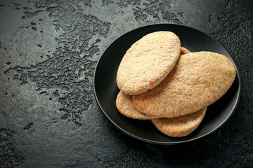 Pita bread on black stone plate on rustic background