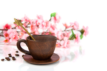 coffee Cup with a spoon, scattered coffee beans on a background of cherry blossoms on a white background