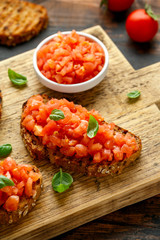 Tomato bruschetta seasoned with basil on a rustic wooden board