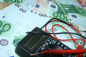 Multimeter on the euro banknotes background. The concept of electricity and electricity bills.