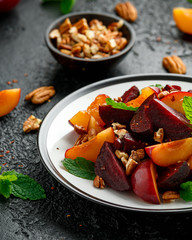 Vegan Plum, beet salad with pecan nuts, mint and herbs on rustic black table