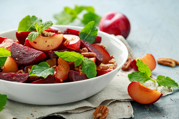 Vegan Plum, beet salad with pecan nuts, mint and herbs in white bowl. healthy summer food.