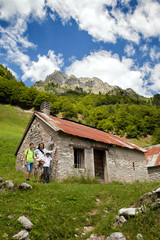 Fototapeta na wymiar Father and children are standing at a mountain hut, Italian Alps