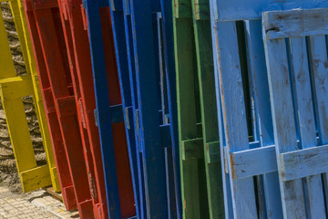 Row of wooden empty pallets painted in different colors, red, green, blue and yellow. 