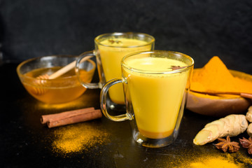 Indian traditional Golden milk with turmeric, ginger, spices, honey. in clear glass glasses....