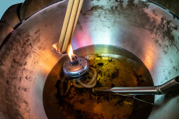 hand holding and burning cense joss stick in temple.