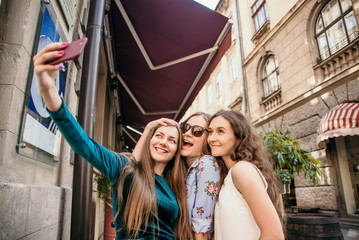 Three young women are walking in the city and having fun. Summer mood