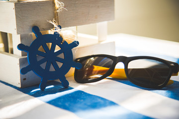 Okulary w blasku słońca leżące na stole nad morzem - obrazy, fototapety, plakaty
