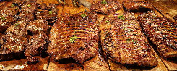 Delicious roasted juicy barbecue pork spare ribs ,charcoal grilled Barbeque steaks on wooden trays in BBQ meat shop at night market for presenting to sale customers ,is famous grilled food recipe