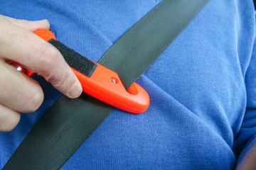 Safety hammer with seat belt cutter being used on seat belt during car crash emergency