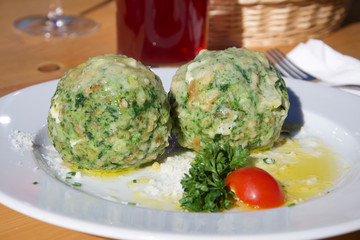 two fresh delicious green spinach dumplings on a plate with tomato and parsley herbs and butter sauce in alto adige alpin restaurant authentic liveauthentic