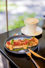Breakfast with bruschetta with ham and cappuccino