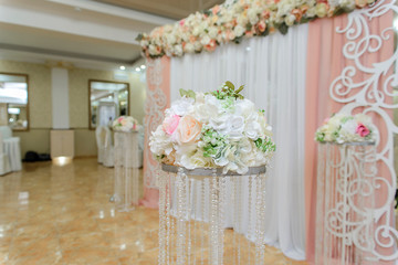 Beautiful bouquet of roses in a vase on a background of a wedding arch. Beautiful set up for the wedding ceremony.