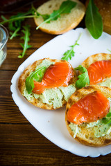 sandwich with fried bun, cheese spread and red fish in a plate