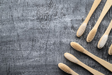Zero waste and beyond plastic concept. Group of eco natural bamboo toothbrushes on a gray wooden background. From above, copy space, horizontal orientation. Layout natural organic hygiene products.