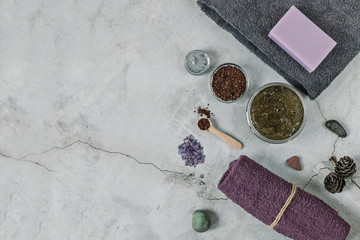 On a gray background are accessories for Spa self-care: body scrub, ground coffee, lavender soap, face mask cream,bath salt ,Terry towels for face and body