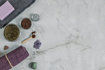 On a gray background are accessories for Spa self-care: body scrub, ground coffee, lavender soap, face mask cream,bath salt ,Terry towels for face and body