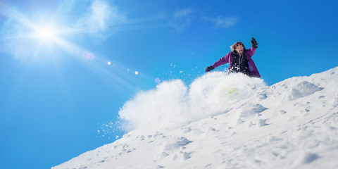 Snowboarder rolls and rides snowboard and make splash of snow