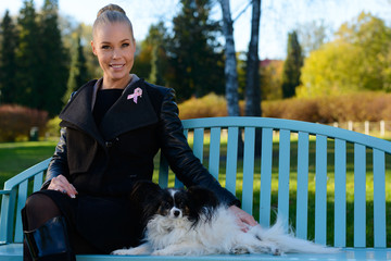 Young happy woman smiling while sitting on bench with cute dog in the park