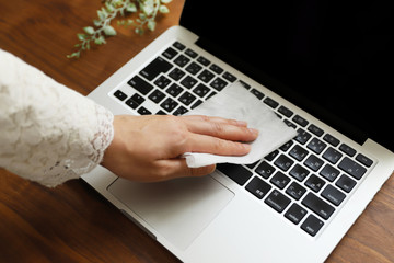 ノートパソコンのキーボードを消毒する女性