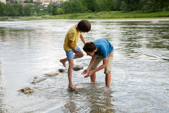 Two boys are playing in mountain river in Italy
