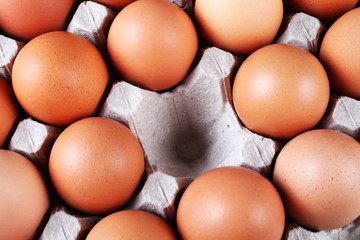 red eggs in a paper tray with one empty cell, macro, soft focus