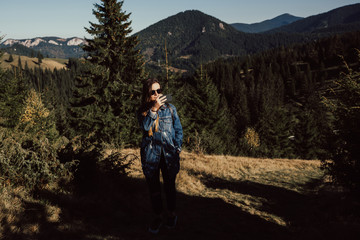 Obraz premium Girl standing on mountain and take pictures on the phone during a hiking trip, the concept of freedom. Travel adventure woman taking photo on smart phone on mountain enjoying beautiful nature.