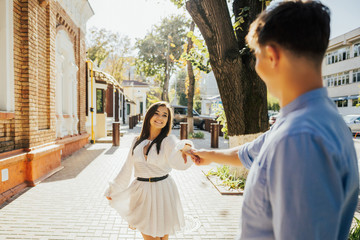 Happy to be together. Rear view of young boy, holding hands and looking at each other with smile while walking through the city street. Her happiness is everything to him. 