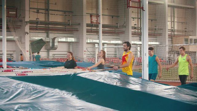 Group of young smiling people on the pole vault training taking their poles 