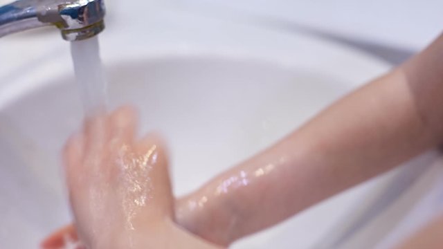 preventing the covid-19 coronavirus pandemic, a little girl washes her hands with soap and a sanitizer