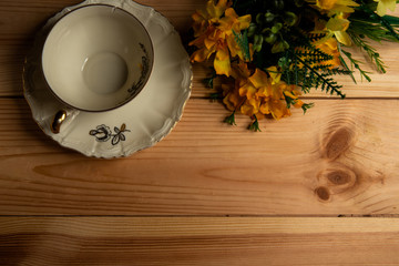 Kompozycja filiżanki z kwiatami na tle sosnowego stołu. © Mariusz