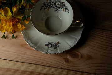 kompozycja filiżanki  z kwiatami na tle sosnowych desek. © Mariusz