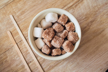 Abowl of brown crystallised sugar cubes from above, in a hipster coffee shop on a rustic brown...
