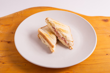 Ham and cheese toast served on a white plate. Fast and tasty snack.
