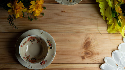 Kompozycja filiżanki i kwiatu na tle sosnowych desek. © Mariusz