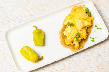 Scrambled eggs on and fermented pepper on  white plate.