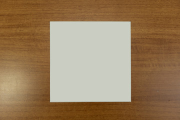 White empty paper square in dark wood background for mockup purposes